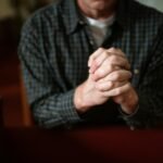 man folding hands in prayer